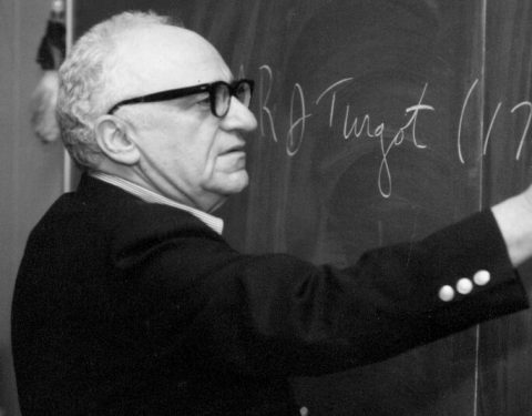 Murray Rothbard escrevendo em um quadro